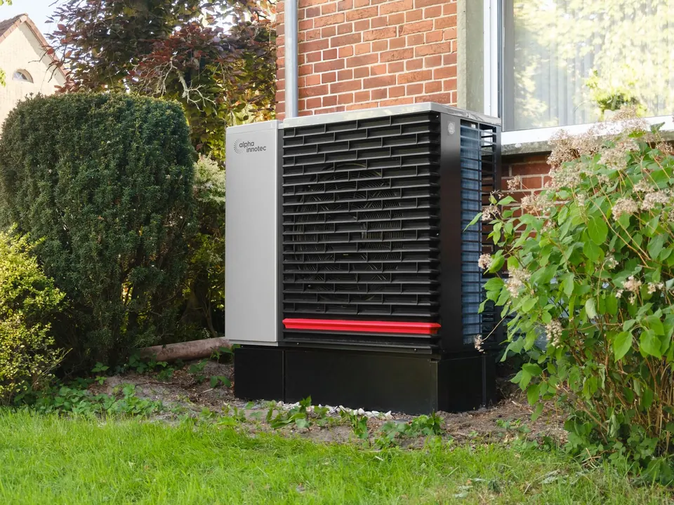 Modern heat pump outdoor unit beside a home garden